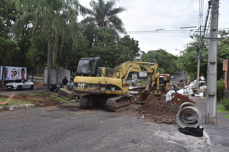 Operarios junto a máquinas CAT en una obra de infraestructura, con un camión y un vehículo pequeño en el fondo.