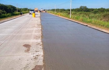 Camión de carga en obra de construcción de carretera, con concreto fraguado y señalización en el paisaje de campo.