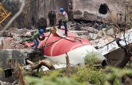 Trabajadores indios retiran los restos del avión de pasajeros de Air India con ayuda de una grúa sobre orugas del lugar del accidente, cerca del Aeropuerto Internacional Sardar Vallabhbhai Patel en Ahmedabad, estado de Gujarat, oeste de la India.