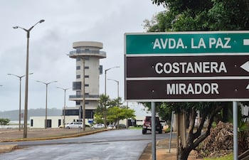 Un cartel guía hacia 'AVDA. LA PAZ', junto a un edificio circular que parece un mirador, en un entorno urbano con un coche estacionado.