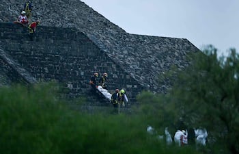 Forenses y miembros de la Cruz Roja trasladan bajan cadáveres de una las pirámides de Teotihuacán.