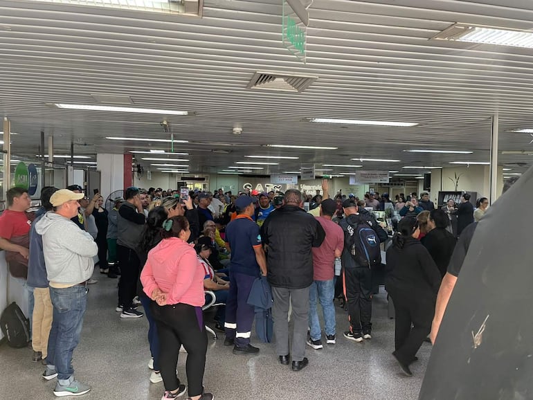 Grupo de funcionarios de la Municipalidad de Asunción se reúne, algunos sosteniendo teléfonos, con expresiones de alegría y tranquilidad.