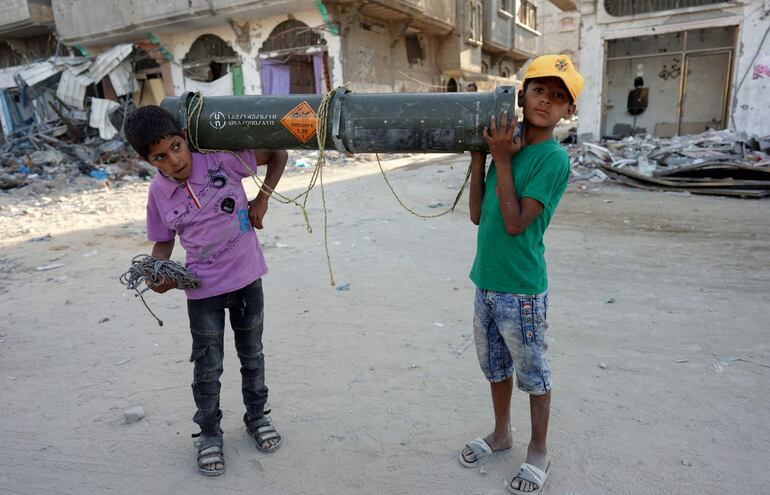 Niños palestinos llevan un contenedor estadounidense de munición vacío en Jan Yunis, en el sur de la Franja de Gaza, el jueves.