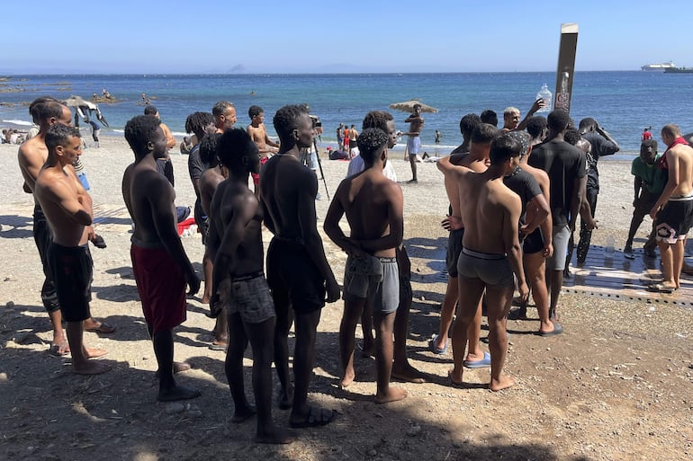 Los jóvenes inmigrantes que duermen en la calle hacen cola para ducharse en la playa del Trampolín, tras acceder a Ceuta el pasado jueves durante la entrada masiva por el espigón fronterizo protagonizada por más de 70.000 personas y que permanecen en la ciudad, entre ellos 528 menores.