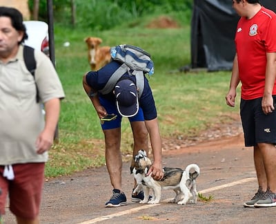 Foto ilustrativa de un peregrino acariciando a un perrito en Caacupé. 