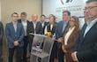 César Sosa en el podio con traje oscuro, mientras once personas, en su mayoría con trajes oscuros, escuchan atentamente en una sala de conferencias.