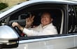 Camilo Pérez López Moreira sonríe al volante de un automóvil plateado, con gesto de paz, en un entorno verde.