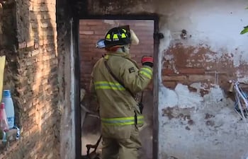 Bomberos voluntarios aplacando el fuego en un incendio de vivienda, en el barrio Kennedy de Lambaré.