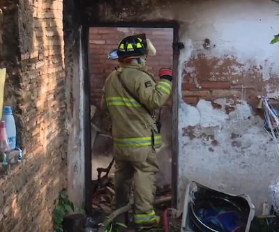 Bomberos voluntarios aplacando el fuego en un incendio de vivienda, en el barrio Kennedy de Lambaré.