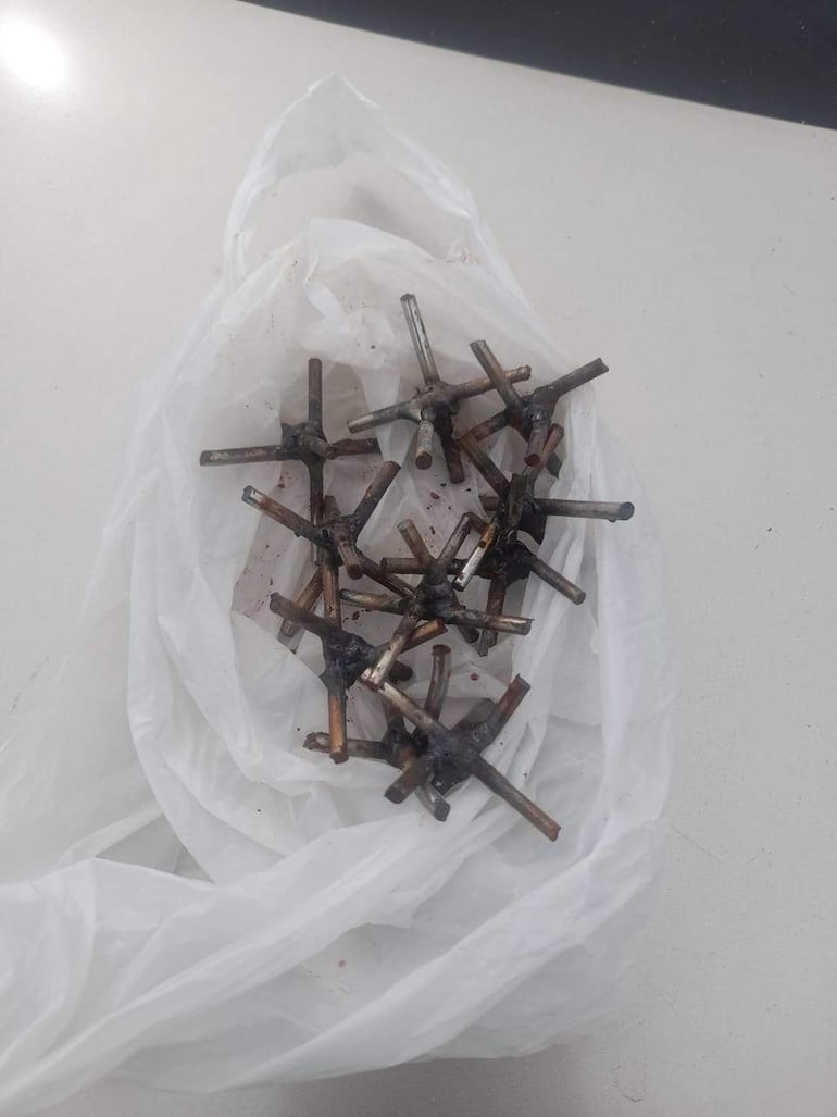 Elementos metálicos oxidados dentro de una bolsa plástica, manchados de un líquido oscuro, sugiriendo posible relación con un incidente violento.