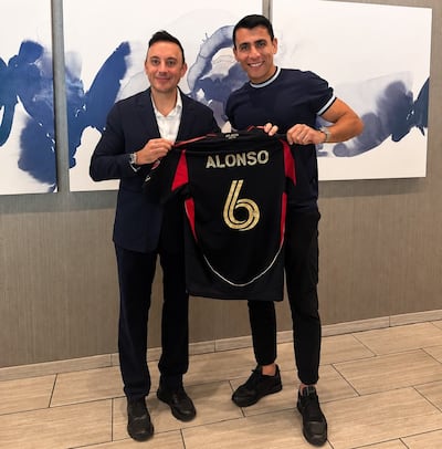 Junior Alonso exhibe la camiseta de su nuevo club, Atlanta United, en compañía de su agente, Diego Serrati.