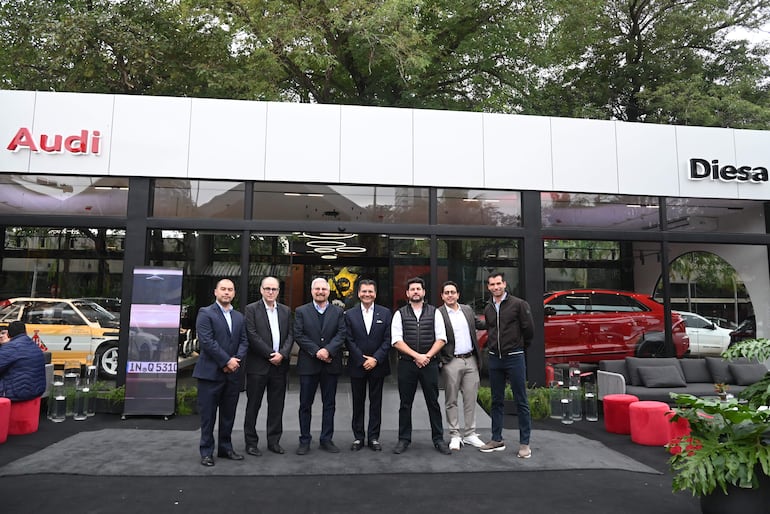 Miguel Carrizosa y seis hombres, todos sonrientes y bien vestidos, posando frente a moderno concesionario Audi.