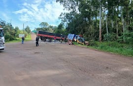 Dos trabajadores observan un camión volcado en la ruta, mientras un camión de bomberos se encuentra en la escena.