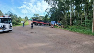 Dos trabajadores observan un camión volcado en la ruta, mientras un camión de bomberos se encuentra en la escena.