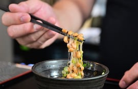 Esta fotografía, tomada el 14 de mayo de 2026, muestra a Kenji Suzuki, propietario de segunda generación del restaurante japonés Suehiro en Los Ángeles, California, levantando natto de un cuenco con palillos.