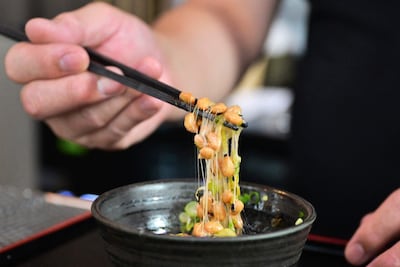 Esta fotografía, tomada el 14 de mayo de 2026, muestra a Kenji Suzuki, propietario de segunda generación del restaurante japonés Suehiro en Los Ángeles, California, levantando natto de un cuenco con palillos.