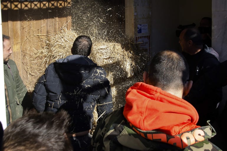 Los agricultores lanzan una bola de paja a la entrada del edificio de la Unidad Regional de Fthiotida, durante una protesta en Lamia, Grecia, el 26 de enero de 2024. 