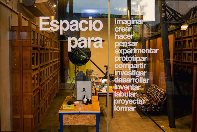 Ambiente interior moderno con mesas de trabajo, estanterías de madera y un sofá colorido, sin personas presentes.