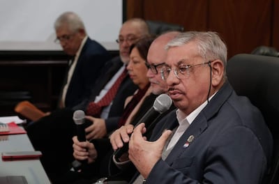 Isaías Ricardo Fretes, canoso y con gafas, habla sosteniendo un micrófono. Otros miembros escuchan atentamente en un ambiente formal.