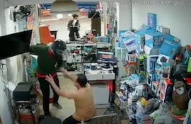 El comerciante se arrodilla ante el delincuente que irrumpió en su negocio para perpetrar el robo.