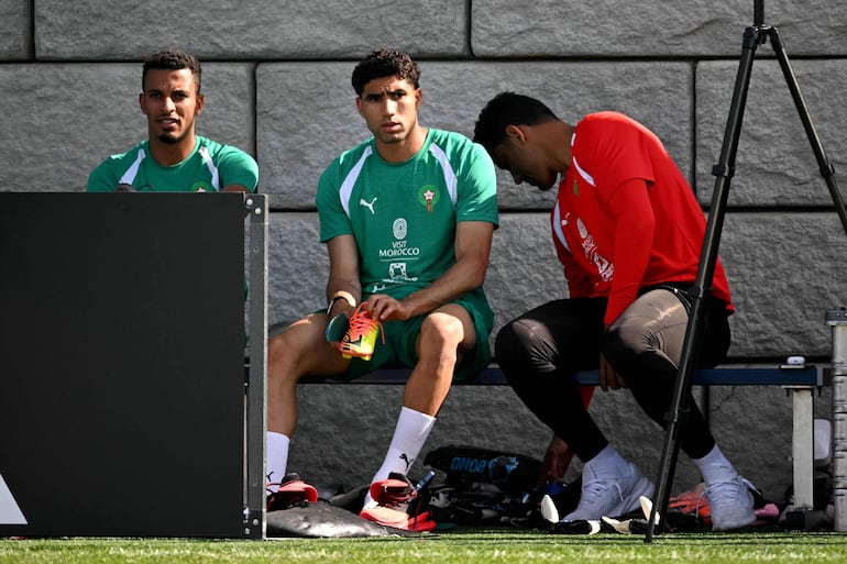 El mediocampista de Marruecos Azzedine Ounahi (I) y el defensor Achraf Hakimi (C) permanecen sentados durante una sesión de entrenamiento para el torneo de fútbol de la Copa del Mundo 2026 en The Pingry School en Basking Ridge, Nueva Jersey.