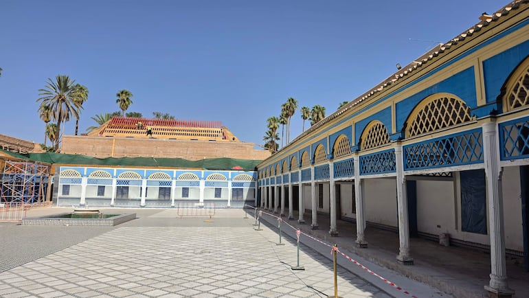 Espacio exterior con paredes azules y arcos decorativos, andamios visibles en el lado izquierdo.