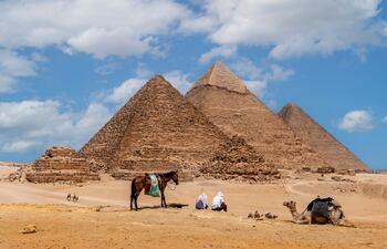 Grupo de turistas observando las vistas panorámicas de las pirámides de Micerino, Kefren y Cheops.