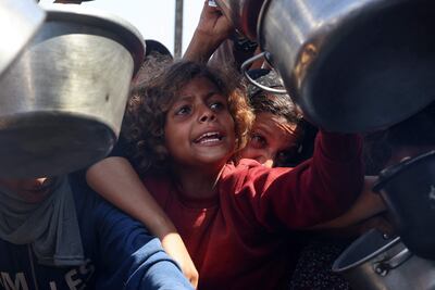 Una niña y varias otras personas intentan conseguir comida en un punto de distribución de ayuda humanitaria ayer jueves en Jan Yunis, en el sur de la Franja de Gaza.