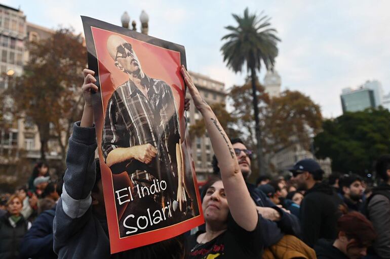 Seguidores del cantante argentino Carlos Alberto 'Indio' Solari sostienen un cartel durante una "misa ricotera" en homenaje tras su fallecimiento este viernes, en Plaza de Mayo en Buenos Aires (Argentina). 