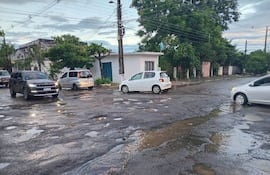 Calle en Santa María con coches en movimiento sobre un pavimento deteriorado y charcos de agua.