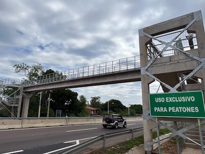 Puente peatonal sin personas, cielo nublado y vegetación al fondo, con un cartel que indica uso exclusivo para peatones.