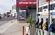 Dispensadores de combustible en estación de servicios con precios en guaraníes, en ambiente urbano tranquilo.