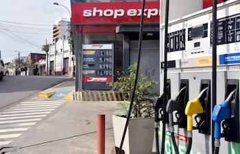 Dispensadores de combustible en estación de servicios con precios en guaraníes, en ambiente urbano tranquilo.