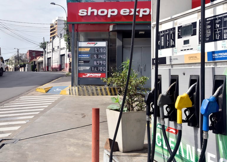 Dispensadores de combustible en estación de servicios con precios en guaraníes, en ambiente urbano tranquilo.
