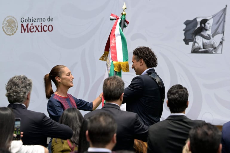 La presidenta de México, Claudia Sheinbaum, entrega la bandera nacional al portero de la selección mexicana Guillermo Ochoa, durante una ceremonia para la selección mexicana de fútbol previa a la Copa Mundial de la FIFA 2026 en el Centro de Alto Rendimiento en la Ciudad de México.
