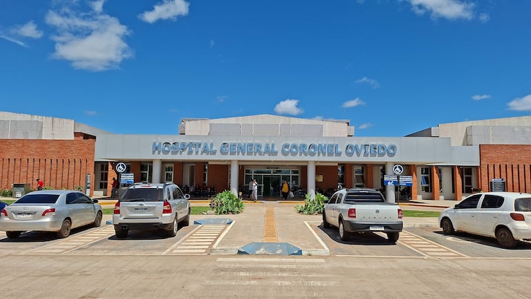 Hospital General Coronel Oviedo con entrada amplia y vehículos estacionados, en un día soleado con cielo azul.