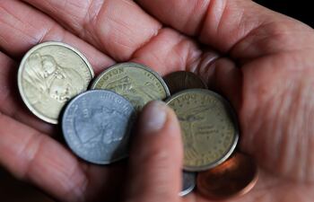 Una persona sostiene monedas de un dólar y centavos de dólar este jueves, en Quito (Ecuador).