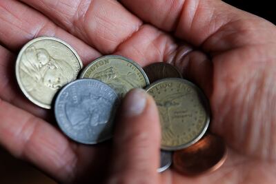 Una persona sostiene monedas de un dólar y centavos de dólar este jueves, en Quito (Ecuador).