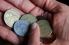 Una persona sostiene monedas de un dólar y centavos de dólar este jueves, en Quito (Ecuador).