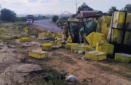 Cajas amarillas y pollos muertos en la carretera tras el accidente del tractocamión en la ruta PY03 cerca de Emboscada.