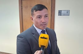Aldo Cantero vestido con traje gris y corbata, habla a un micrófono en un entorno formal moderadamente iluminado.