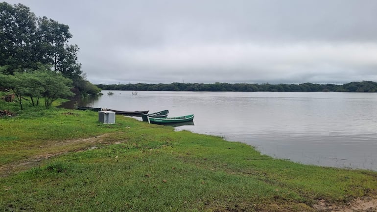 Tres canoas en orilla de río, cielo nublado y vegetación verde alrededor, sin presencia humana.