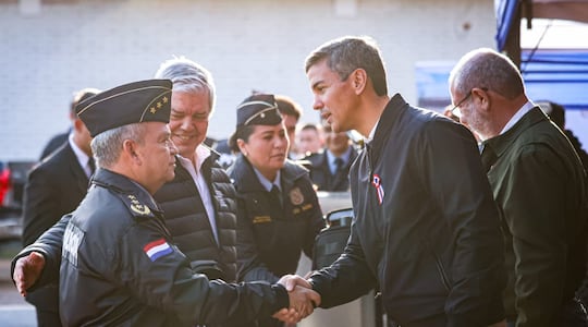 Tras retornar de Filipinas, el presidente Santiago Peña saludó al comandante de la Policía Nacional, Crio. Gral. César Silguero. Sonríe el ministro de Interior, Enrique Riera. El mandatario asistió al acto de entrega de chalecos para la fuerza policial, adquiridos por Itaipú. (Foto gentileza).