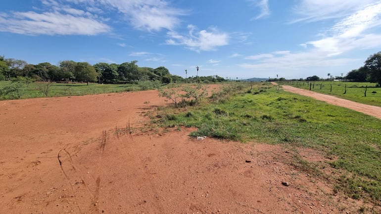 Paisaje natural con terreno de tierra roja y áreas verdes, sin personas presentes.