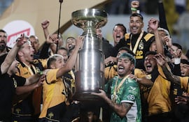 Luis Riveros (i) celebra el brazo en alto junto al capitán Diego “Mono” Sánchez, quien levanta el trofeo de la Supercopa de Chile. (EFE)