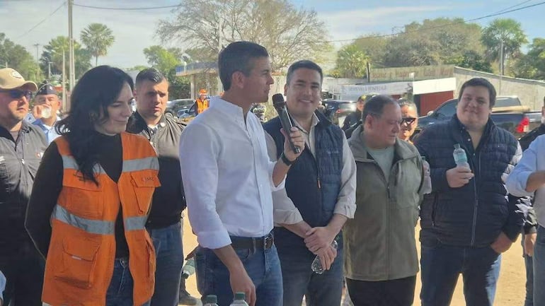 Santiago Peña habla con micrófono, Claudia Centurión en chaleco anaranjado a su izquierda, y Federico Méndez sonriente a su derecha.