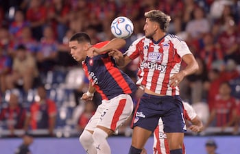 El defensor de Cerro Porteño, Marcelo Chaparro, y el mediocampista de Junior, Daniel Rivera, luchan por el balón durante el partido de fútbol de la fase de grupos de la Copa Libertadores entre Cerro Porteño de Paraguay y Junior de Colombia, en el estadio La Nueva Olla en Asunción.