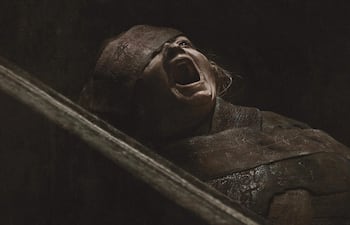 Personaje en primer plano con expresión de enojo, gritando en un ambiente oscuro y con luces tenues.