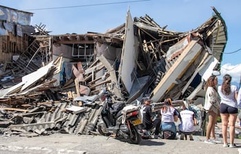 Personas observan una edificación destruida por un terremoto de magnitud 7,4 este lunes, en Manizales (Colombia). El presidente de Colombia, Abelardo de la Espriella, afirmó que el terremoto que sacudió la mayor parte del país, deja una cifra parcial de 111 fallecidos y una gran destrucción en al menos cinco departamentos.