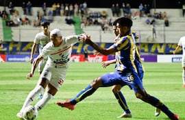 El extremo de Nacional, Orlando Gaona Lugo intenta escapar del volante de Sportivo Luqueño, Ángel "Pirayú" Benítez.